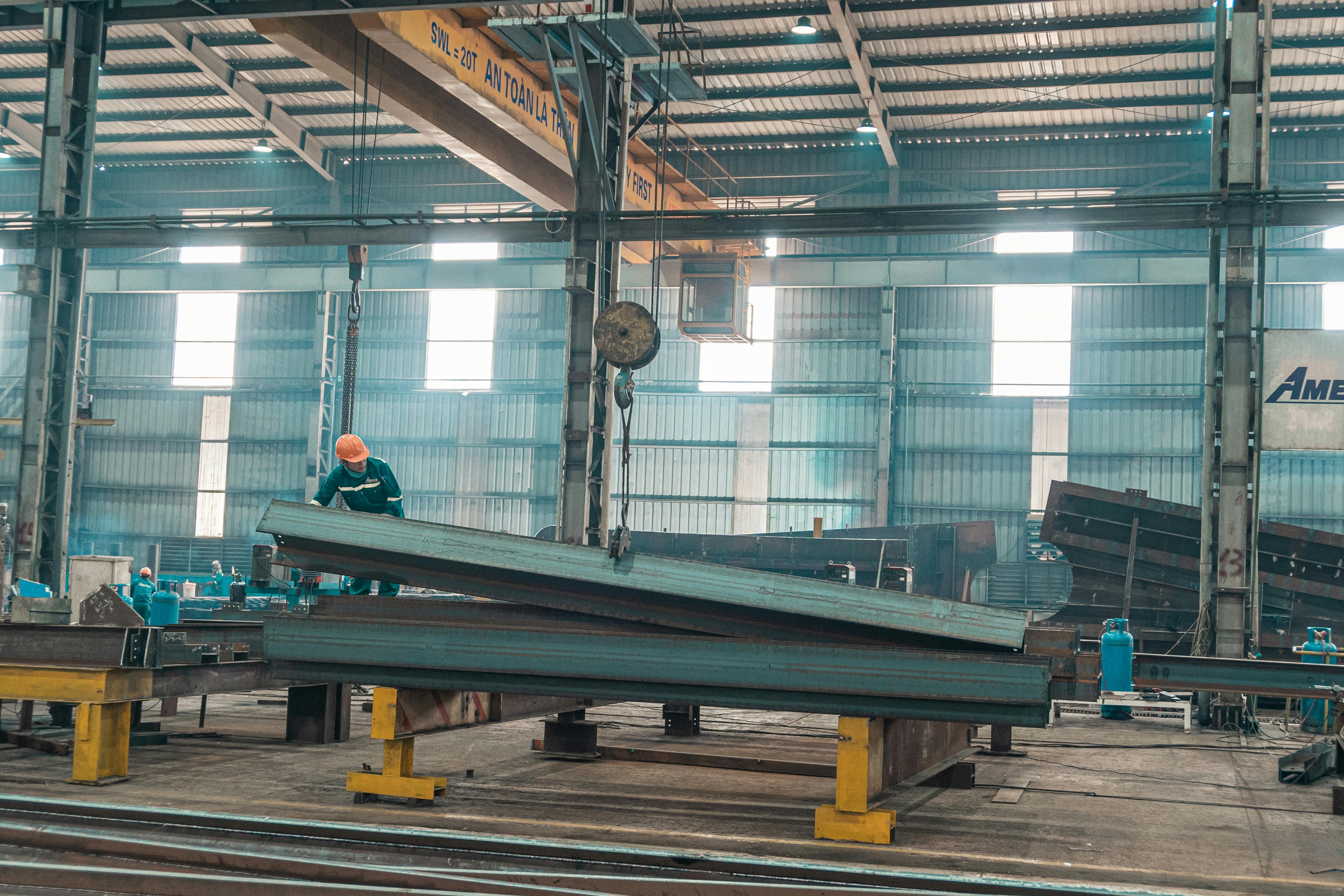 A welder working on a large steel component wearing PPE gear.